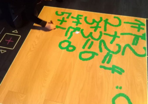 Chłopiec pisze działania na podłodze interaktywnej.