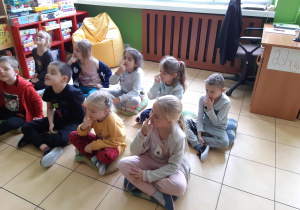 Dzieci siedzą na poduchach.