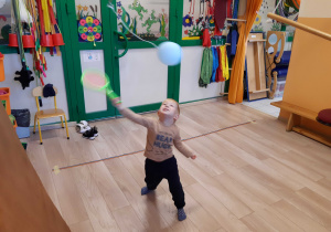 Chłopiec odbija rakietką zawieszonego balona.