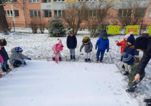 Dzieci w ogrodzie zimą.