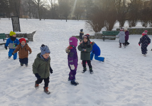 Dzieci bawią się w parku na śniegu.