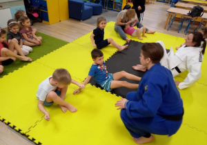Dzieci trenują judo z trenerem.