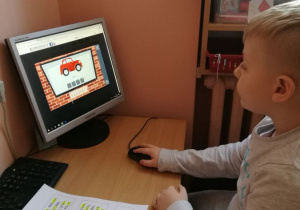 Dziecko uczy się czytać wykorzystując grę komputerową.