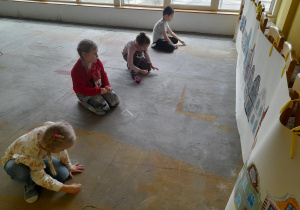 Dzieci rysują kredą kamienicę.