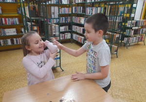Chłopiec kładzie monetę na ręku koleżanki.