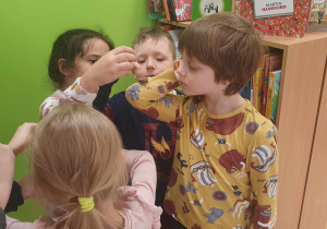 Dzieci układają monety na ręku kolegi.