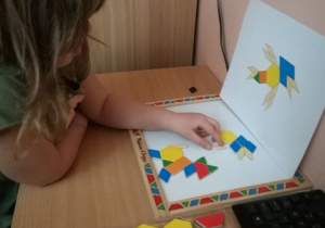Dzieci układają obrazki z figur na tablicy magnetycznej.