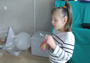 Dziewczynka puszcza bańki mydlane.