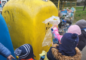 Dzieci przy pojemnikach do segregacji śmieci.