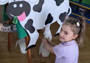 Dziewczynka doi krowę.