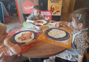 Dzieci przygotowują pizzę.