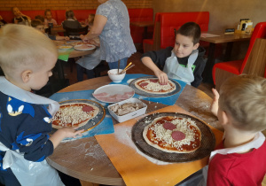 Chłopcy tworzą swoją pizzę.