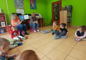 Dzieci siedzą na poduszkach i słuchają opowiadania o Chrupku.