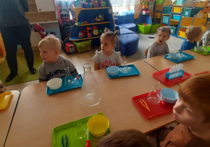 Dzieci siedzą przy stolikach i czekają na warsztaty.
