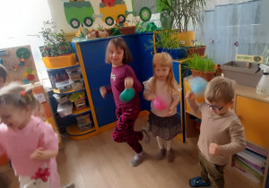 Dzieci podskakują trzesąc balonami.