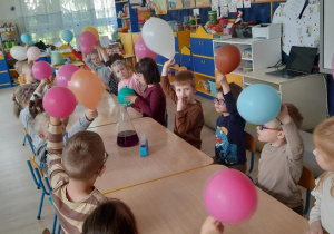 Dzieci pokazują balony, które udało się napompować za pomocą suchego lodu.