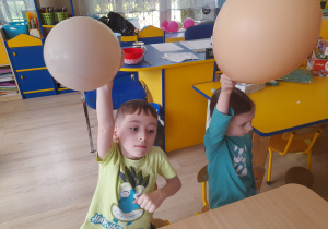 Dzieci trzymają w dłoniach balony.