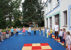 Dzieci stoją w kole z nauczycielkami.