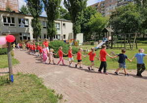 Dzieci gęsiego idą na boisko.