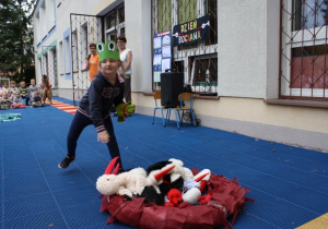 Dziewczynka wrzuca maskotę bociana do gniazda.