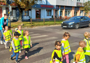 Dzieci przechodzą po pasach oraz przy zielonym świetle dla pieszych.