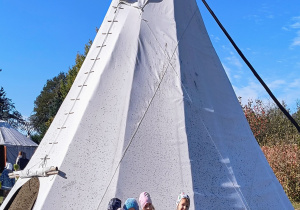 Dzieci stoją przed tipi.