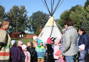 Dzieci stoją przed indiańskimi tipi.