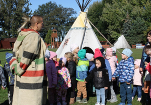 Dzieci stoją przed indiańskimi tipi.