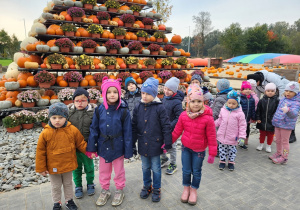 Dzieci pozują do zdjęć, na tle dekoracji jesiennych z dyń.