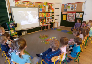 Dzieci ogladają film na tablicy multimedialnej.