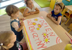 Dziewczynki malują planszę z napisem - Dzień dziewczyny.