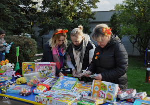 Rodzice na stanowisku z zabawkami i grami.