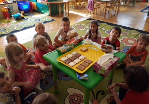 Dzieci siedzą na dywanie, na stoliku leży wzór deseru "zebra"