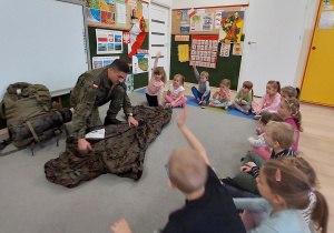 Żołnierz pokazuje dzieciom swój ekwipunek.