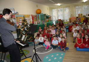 Dzieci słuchają kolęd wykonywanych przez studentów.