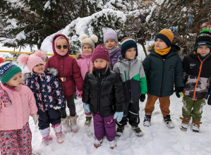 Dzieci w ogrodzie przedszkolnym na tle karmników dla ptaków.