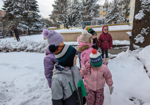 Dzieci spacerują po terenie ogrodu w poszukiwaniu karmników.