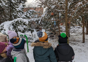 Dzieci spacerują po terenie ogrodu w poszukiwaniu karmników.