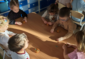 Dzieci ozdabiają upieczone babeczki.