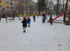 Dzieci biegają i rzucają się śnieżkami.