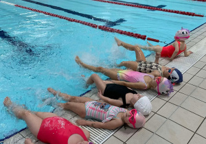 Dzieci wykonują ćwiczenia przed zanurzeniem się w wodzie.