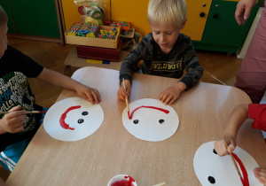 Dzieci malują buźki z uśmiechem.