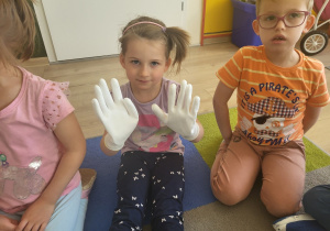 Dziewczynka przymierza rękawice ochronne.