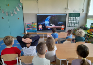 Dzieci oglądają film edukacyjny o Ziemi.