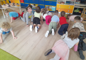 Dzieci naśladują dinozaury w zabawie ruchowej.