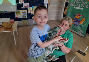 Chłopiec pozuje do zdjęcia z dinozaurem.