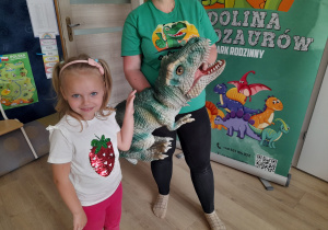 Dziewczynka pozuje do zdjęcia z dinozaurem.