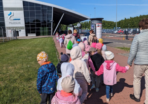 Dzieci spacerują w kierunku budynku lotniska.