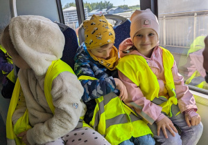 Dzieci jadą autobusem lotniskowym po terenie portu lotniczego.