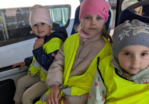 Dzieci jadą autobusem lotniskowym po terenie portu lotniczego.